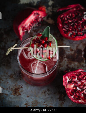 Alcoholic cocktail garnished with pomegranate seeds on dark moody background Stock Photo