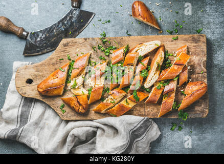 Turkish oriental pizza pide with cheese and spinach chopped in slices on wooden board over grey stone background, top view Stock Photo