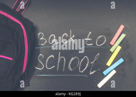 Back to school message on Blackboard inscribed with colorful chalk for background. Backpack Stock Photo