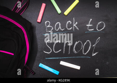 Back to school message on Blackboard inscribed with colorful chalk for background. Backpack Stock Photo
