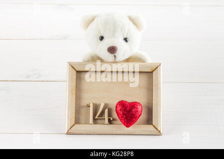 White teddy bear holding plate with hearts. Concept on 14 February Stock Photo