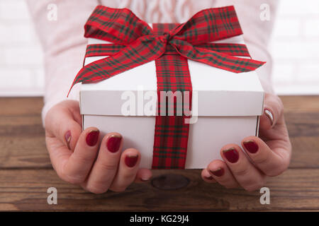 Woman holding presents gift box laid on wooden table background Stock Photo