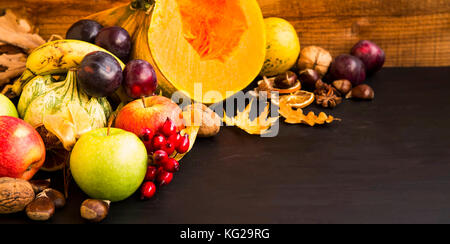 Fall fruits and vegetables harvesting on wooden tray, pumpkins, apples, plums, walnuts and chestnuts, fall decoration on wooden background Stock Photo