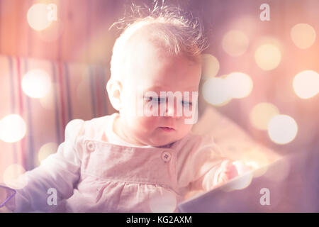 Beautiful baby looking surprise among fairy lights in pink toned colors