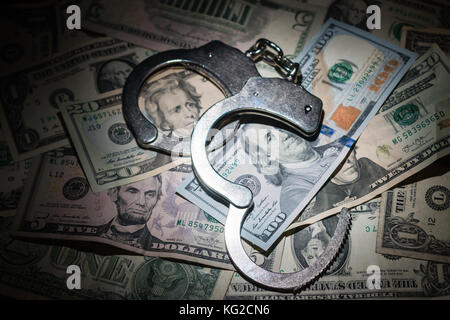A pair of open handcuffs on a pile of American Dollars. Stock Photo