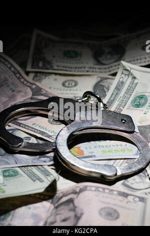 A pair of closed handcuffs on a pile of American Dollars Stock Photo