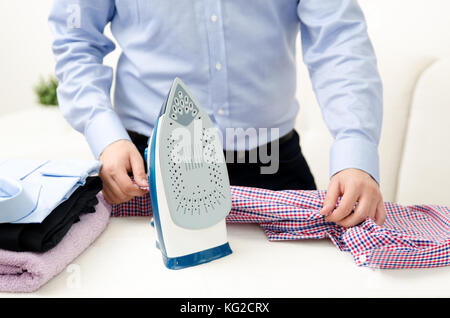 Man ironing shirt on ironing board. Steaming blue iron. Clothes ironing board household concept Stock Photo