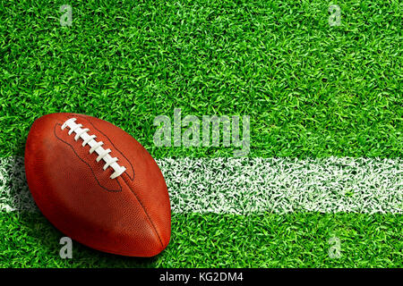 Football on field with white line marking and copy space. Line represents goal line in the end zone, inbound line or advancing yard line on the field. Stock Photo