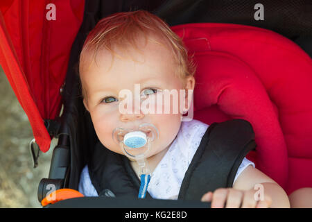 Cute baby with pacifier sitting in the stroller Stock Photo