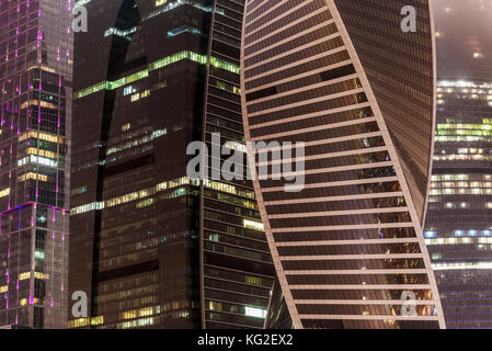 Abstract hi-tech background of fragment modern elevation office buildings of steel and glass with lights switched at night in the fog Stock Photo