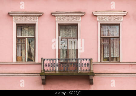 Three windows in a row and balcony on facade of the urban apartment building front view, St. Petersburg, Russia Stock Photo