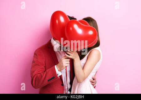 Couple kissing behind balloons Stock Photo