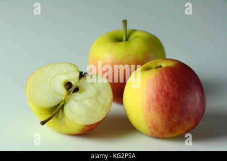 Three ripe apples on white background - one apple cut in half Stock Photo
