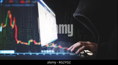 Internet crime and speculate stock concepts, Hacker working on computer laptop with downward stock graph background Stock Photo