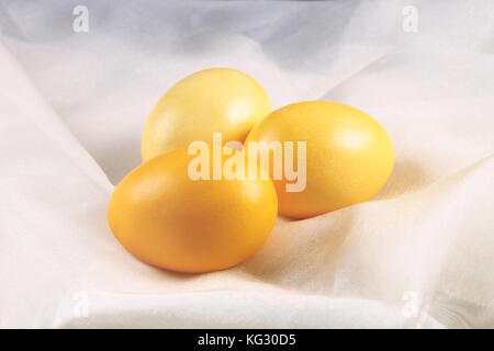 Yellow Easter eggs lying on a silk fabric. Stock Photo