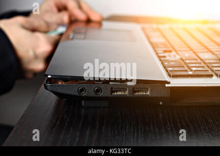 Closeup shot of male hands working on disassembling and cleaning circuit board in laptop using brush Stock Photo