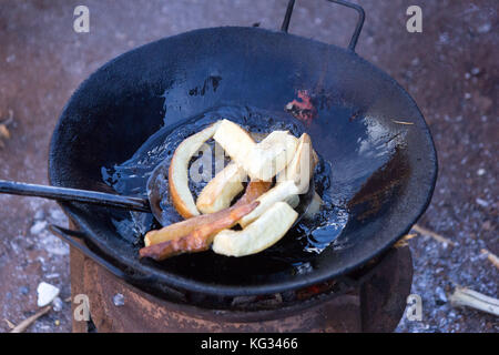 Frying cassava in oil in a pan on fire stove. Photo taken in Najja, Uganda on 9 May 2017. Stock Photo
