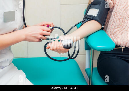 Close up view of female medicine doctor measuring blood pressure to her patient. Hands close up. Healthcare, healthy lifestyle and medical service concept. Space for text Stock Photo