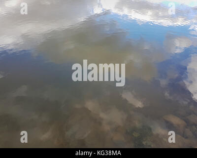 Thunderous blue sky with white clouds is reflected in the water surface of a large puddle. Stock Photo