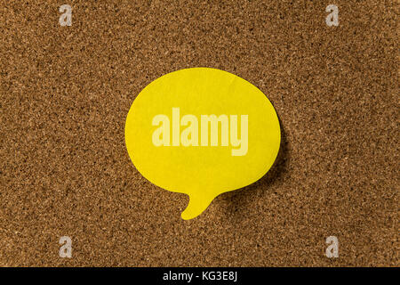Yellow sticker with shape of speech bubble on cork board Stock Photo