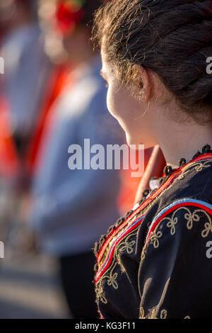 PERNIK, BULGARIA - JANUARY 27, 2017: Young woman in Bulgarian folklore costume with traditional decorations is marching and smiling at Surva, the Inte Stock Photo