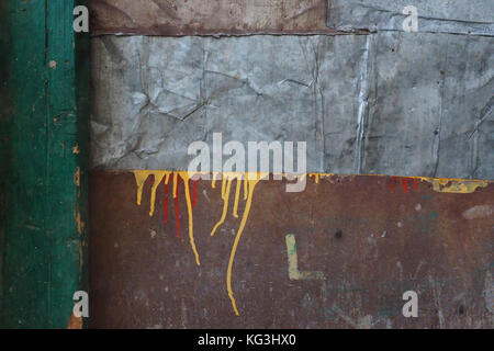 Abstract background of rectangles of brown plywood, sheet of gray metal and green bar on the right, over the surface of plywood yellow streaks of oil  Stock Photo