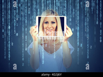Happy woman holding tablet with her face displayed on a screen isolated on binary code background Stock Photo
