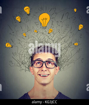 Brain connections. Excited man looking up at many ideas light bulbs above head isolated on gray wall background. Eureka concept Stock Photo