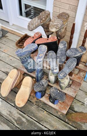 Boots on drying rack outside farmhouse at Wise Acres Organic Farm, a U-pick strawberry agriculture operation in Indian Trail, North Carolina, USA Stock Photo