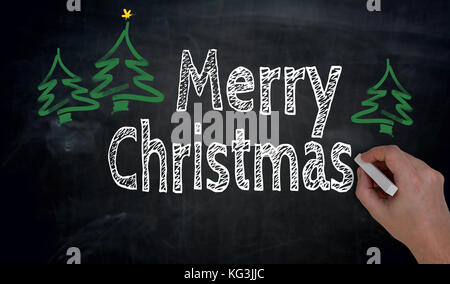 Merry Christmas is written by hand on blackboard. Stock Photo