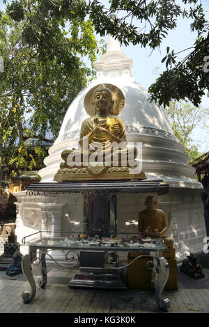 Colombo Sri Lanka Slave Island Gangaramaya Temple Gold Buddha Statue with the Dharmachakra Mudra and seated in the Padmasana Position in front of Dago Stock Photo