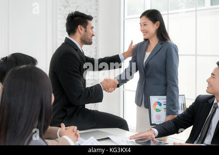 Asian businessman and businesswoman shaking hands in conference room. Business people shaking hands agreement concept. Stock Photo
