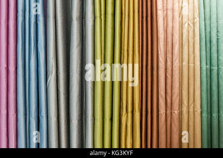 Colorful curtain samples hanging from hangers on a rail in a display in a retail store Stock Photo