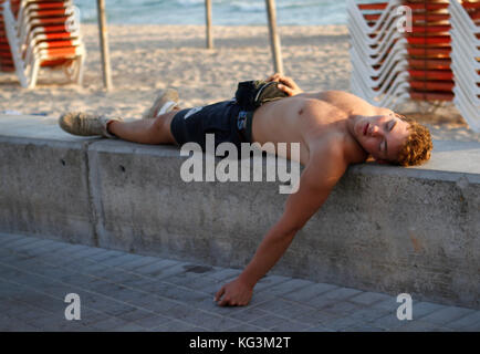 Tourist sleeping on the beach of Arenal, in Mallorca. In an area known for thefts of tourists who fall asleep on the beach after having drunk a lot of Stock Photo