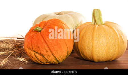 Three multi-colored pumpkins and cones on a wooden table. Close up, small depth of sharpness Stock Photo