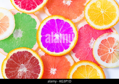 The multi-colored citrus of artificial color cut by circles lies on a table. Orange, lemon, grapefruit. Colors not usual for a citrus. Close up, small Stock Photo