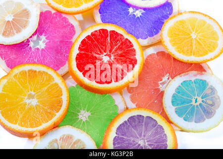 The multi-colored citrus of artificial color cut by circles lies on a table. Orange, lemon, grapefruit. Colors not usual for a citrus. Close up, small Stock Photo