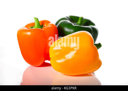 Fresh pepper on a white background. Green, yellow and orange sweet pepper, are reflected in a white background Stock Photo