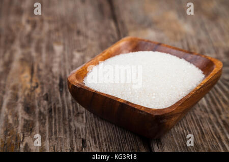 Sugar in a wooden bowl on an old wooden background Stock Photo