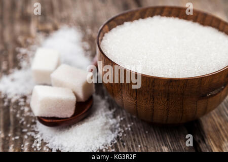 Sugar in a wooden bowl and a spoon on an old wooden background. Stock Photo