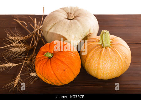 Three multi-colored pumpkins and cones on a wooden table. Close up, small depth of sharpness Stock Photo