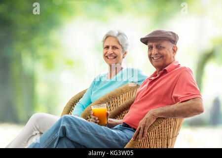 Senior couple sitting outdoors on wicker chair Stock Photo