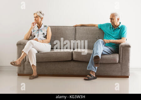 Angry senior couple sitting apart on sofa Stock Photo
