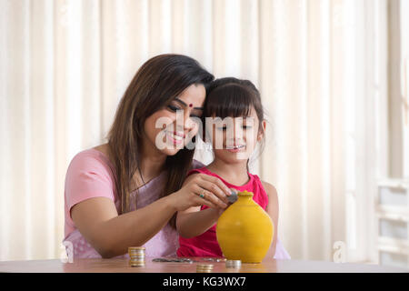 Mother and daughter filling piggy bank Stock Photo