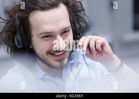 young smiling male call centre operator doing his job with a headset Stock Photo