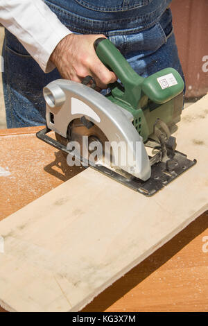 Carpenter's workshop. Carpenter cuts the OSB Carpenter slashes the board using an electric saw Construction worker crosses a board with a circular saw Stock Photo