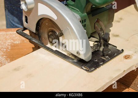 Carpenter's workshop. Carpenter cuts the OSB Carpenter slashes the board using an electric saw Construction worker crosses a board with a circular saw Stock Photo