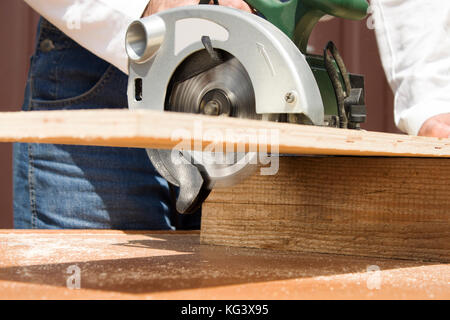 Carpenter's workshop. Carpenter cuts the OSB Carpenter slashes the board using an electric saw Construction worker crosses a board with a circular saw Stock Photo