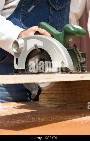 Carpenter's workshop. Carpenter cuts the OSB Carpenter slashes the board using an electric saw Construction worker crosses a board with a circular saw Stock Photo