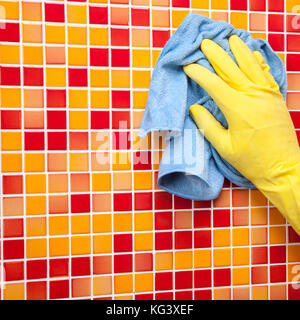 Person doing chores in bathroom at home cleaning tiled wall with microfiber towel Stock Photo